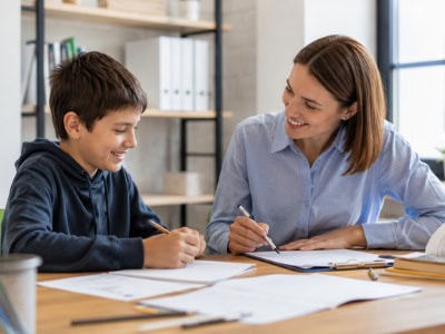 math-tutoring-success-story Fifth-grade student smiling during a one-on-one math tutoring session, working through problems with a supportive tutor at a bright study table in a welcoming learning environment.