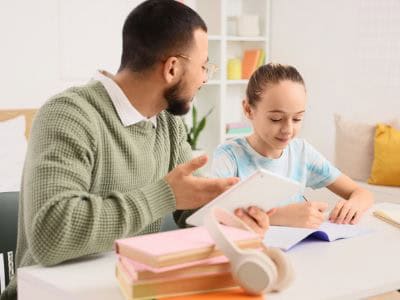 Adult helping a child with schoolwork at a table, illustrating individualized learning support for neurodivergent students and children with learning differences or learning disabilities.